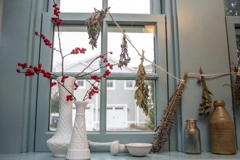 The kitchen window is festive with berries and dried herbs among a collection of milk glass at the Thomas Maull House.